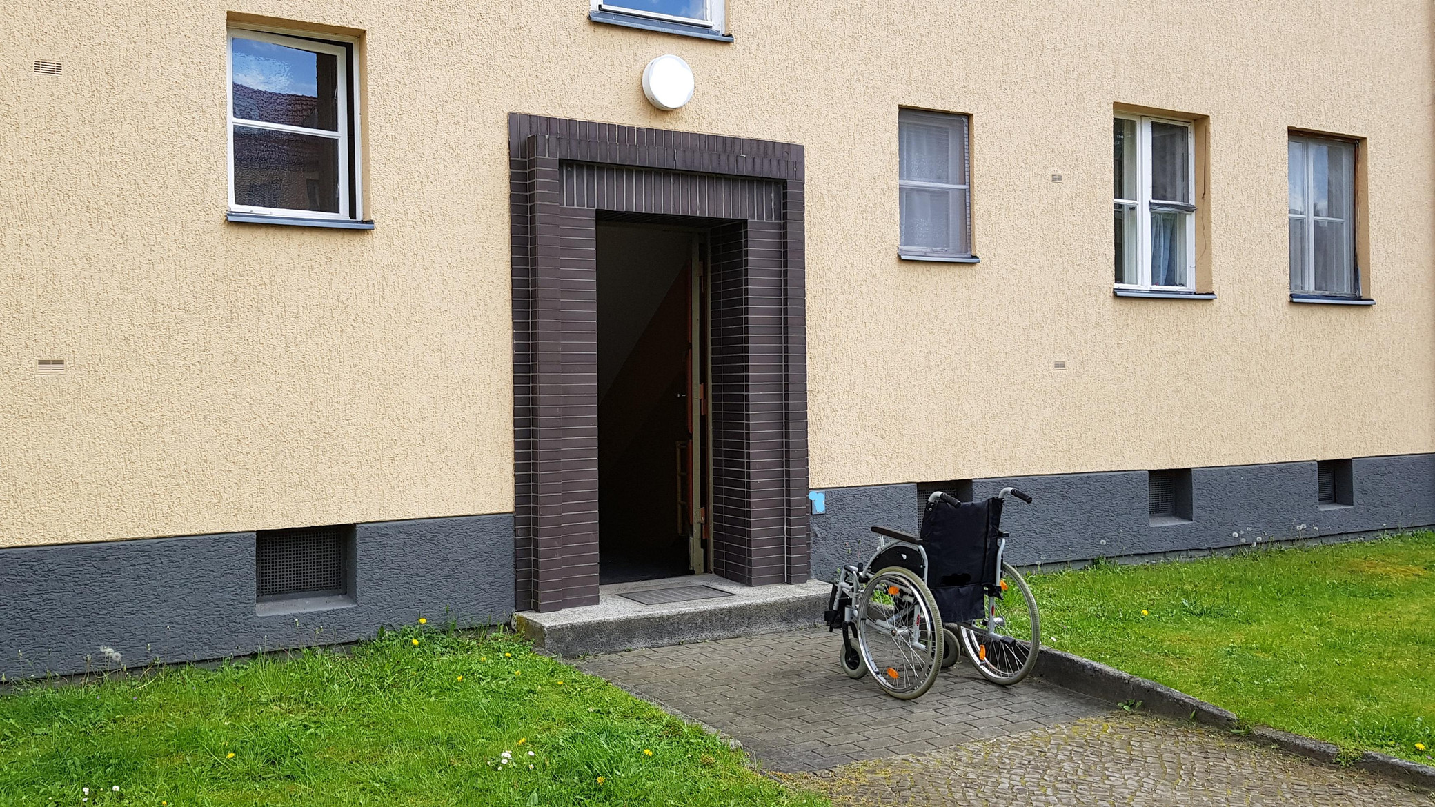 Rollstuhl vor Hauseingang mit Stufe